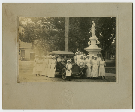 [Club girls in uniforms stand around an automobile with Virginia P. Moore sitting inside] Miniature