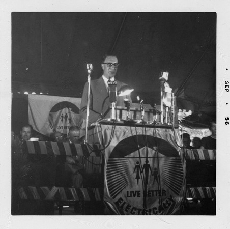 Estes Kefauver speaking from podium draped with “Live Better Electrically” banner Miniaturansicht